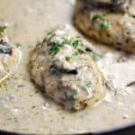 Creamy Mushroom Chicken breasts in a cast iron skillet surrounded by sauce