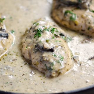 Creamy Mushroom Chicken breasts in a cast iron skillet surrounded by sauce