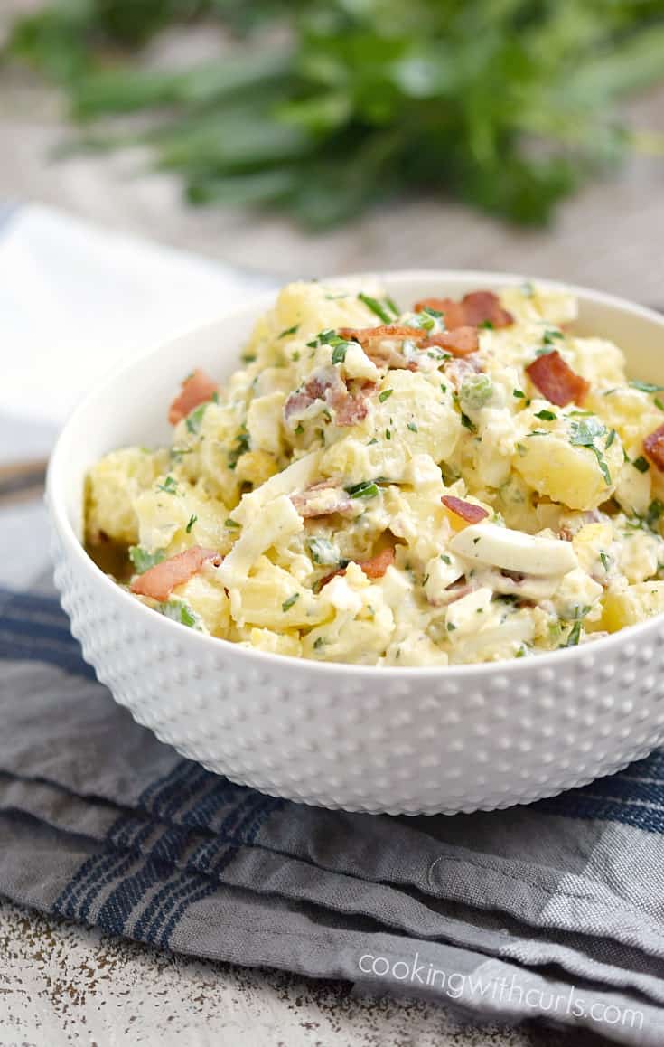 Bacon Potato Salad sprinkled with chopped bacon in a serving bowl.
