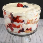 Triple berry trifle in footed serving bowl.
