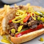 Italian Beef piled on a sandwich roll and topped with sauteed bell peppers