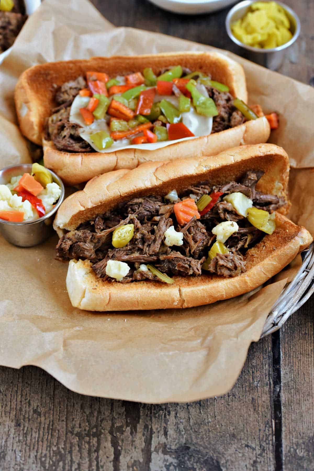 Two Italian beef sandwiches on a parchment lined basket.