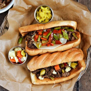 Two Instant Pot Italian beef sandwiches on a parchment lined basket.