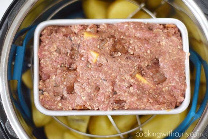 Bacon Cheeseburger Meatloaf in a loaf pan over potato chunks in an Instant Pot.