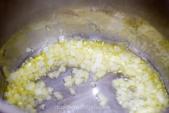Diced onion simmering in oil inside an Instant Pot.
