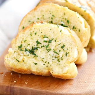 The Best Garlic Bread sliced on a wood board.