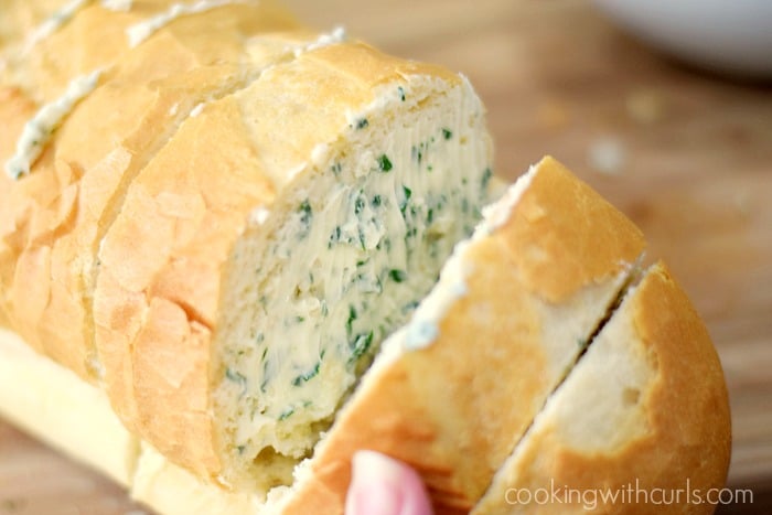 Garlic butter spread inside the cuts in the loaf of French bread.