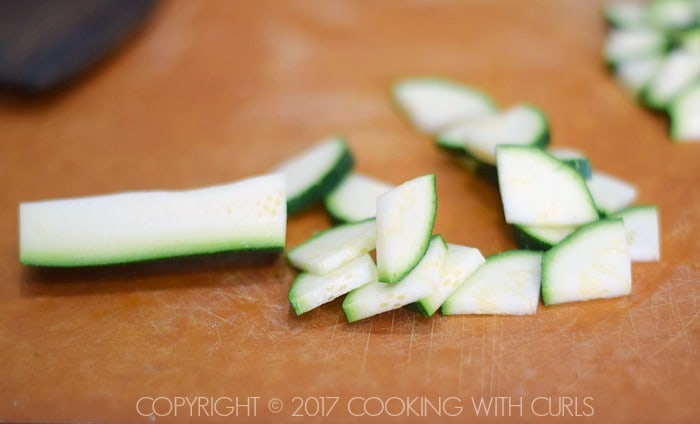 Zucchini wedge thinly sliced on a cutting board.