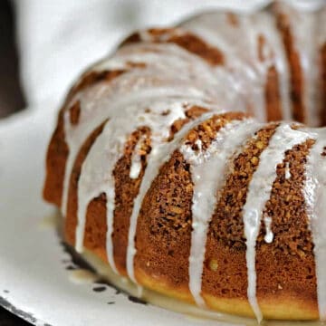 Bundt-shaped Cinnamon-Pecan Coffee Cake recipe topped with glaze on a serving platter.