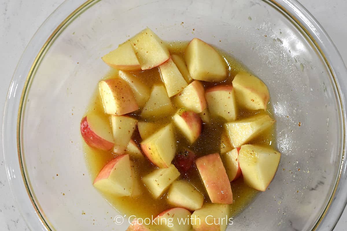 Chopped apples in a mixing bowl with apple cider vinaigrette. 