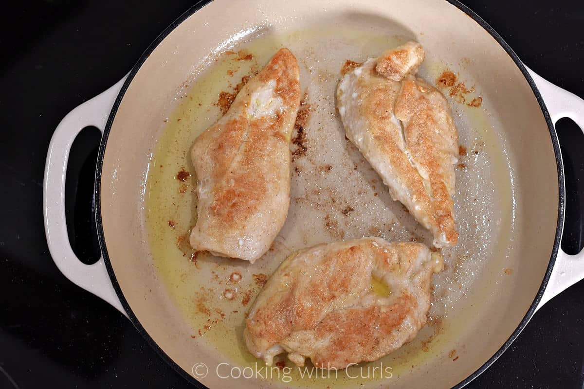 Cooked chicken breasts in a skillet with oil. 