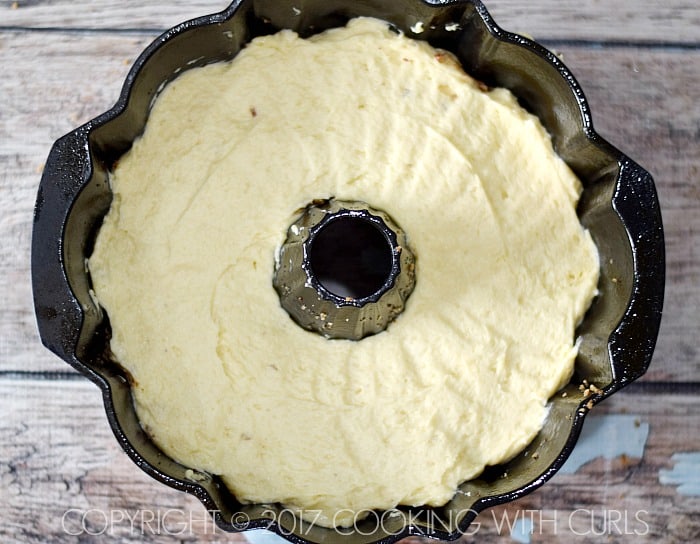 Looking down on cake batter evenly spread out in the bundt pan .