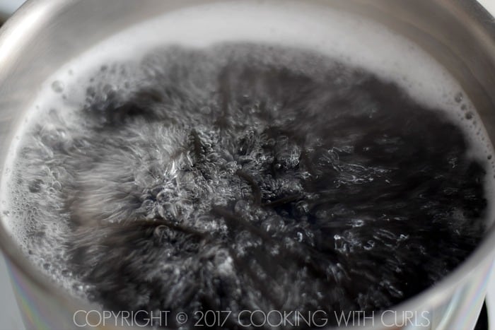Black pasta boiling in a saucepan of water.