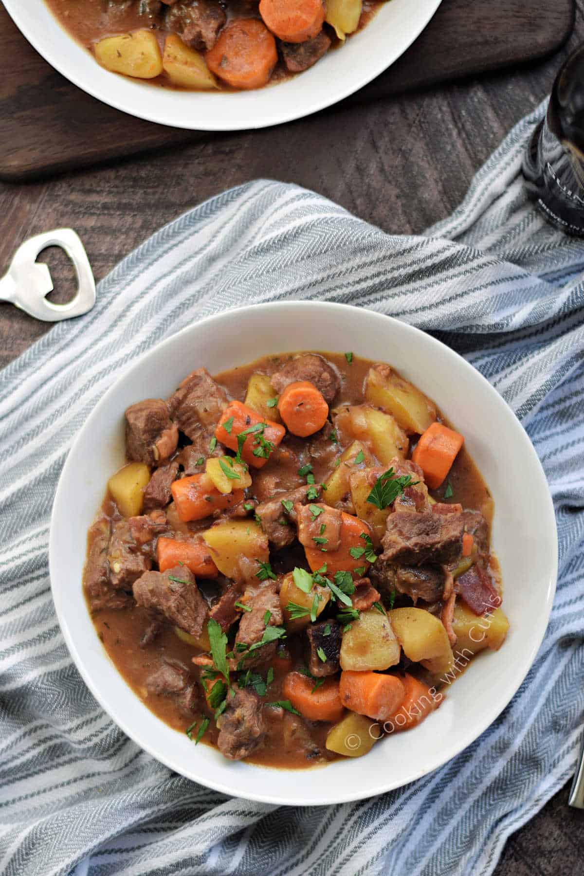 Looking down on two bowls of beef stew with carrots and potatoes.