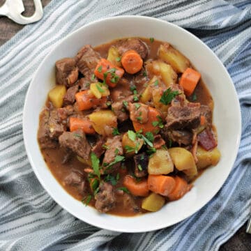 Looking down on a bowl of beef stew with carrots, potatoes.