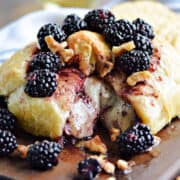 Melted cheese surrounded by puff pastry topped with blackberries and walnuts.