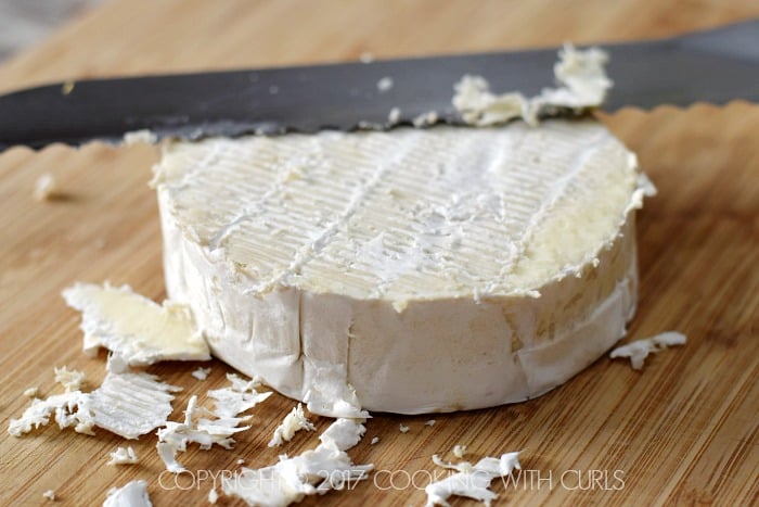 Brie cheese with the rind scraped off sitting on a cutting board.