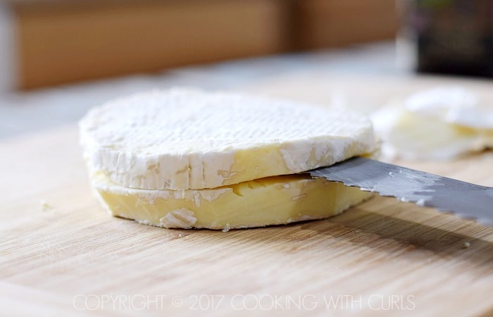 A round brie sliced in half with a bread knife.