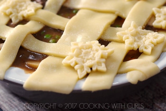 Snowflake pie crust cut outs randomly placed on top of the pot pie filling.