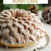 A glazed, Spiked Eggnog Bundt Cake recipe on a serving platter sitting in front of a Christmas tree with title graphic across the top.