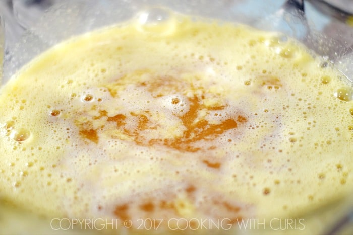 Brandy and bourbon added to the beaten eggs and sugar in a large bowl.
