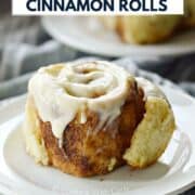 Two cinnamon rolls topped with cream cheese icing on small plates with title graphic across the top.