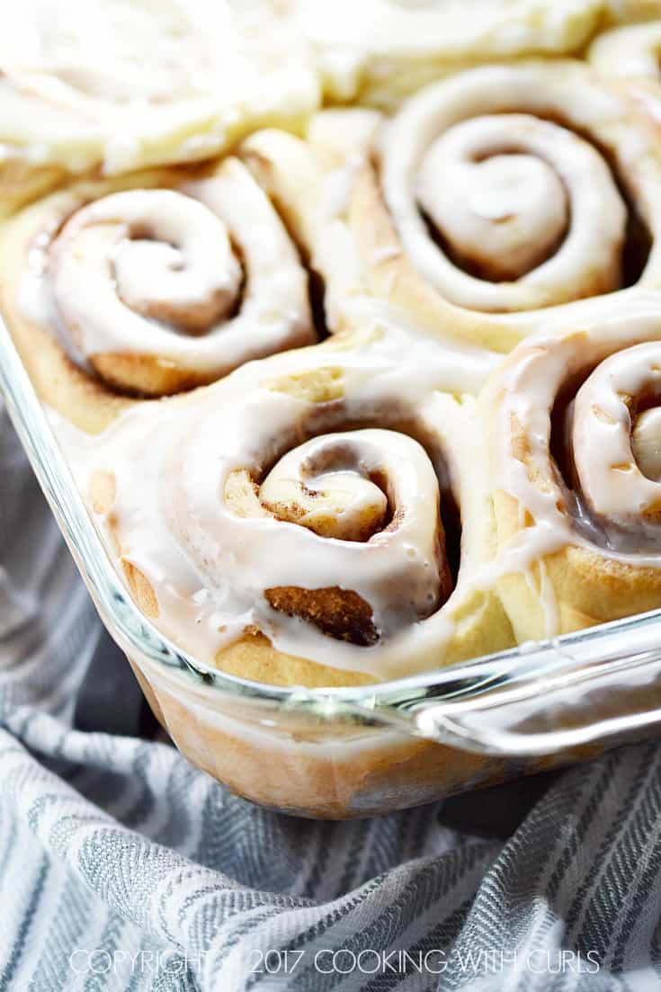 Baked cinnamon rolls topped with vanilla glaze in a baking dish.