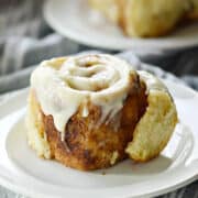 Two cinnamon rolls topped with cream cheese icing on small plates.