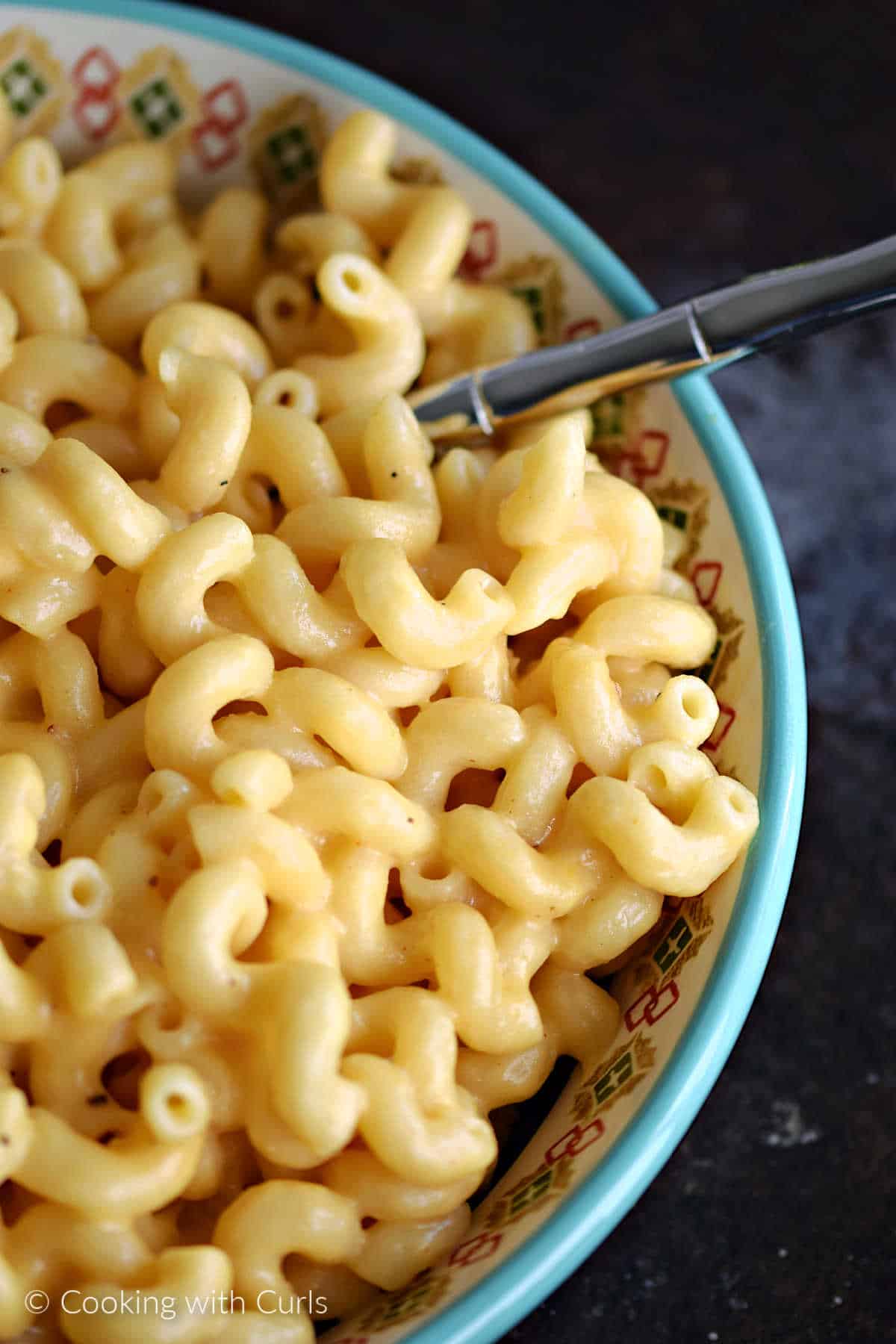 Creamy mac and cheese in a serving bowl with a large spoon.