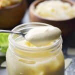 Caesar Salad Dressing in a glass jar with a spoonful of dressing sitting on top