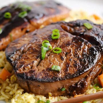 A steak and a piece of salmon on a bed of fried rice.