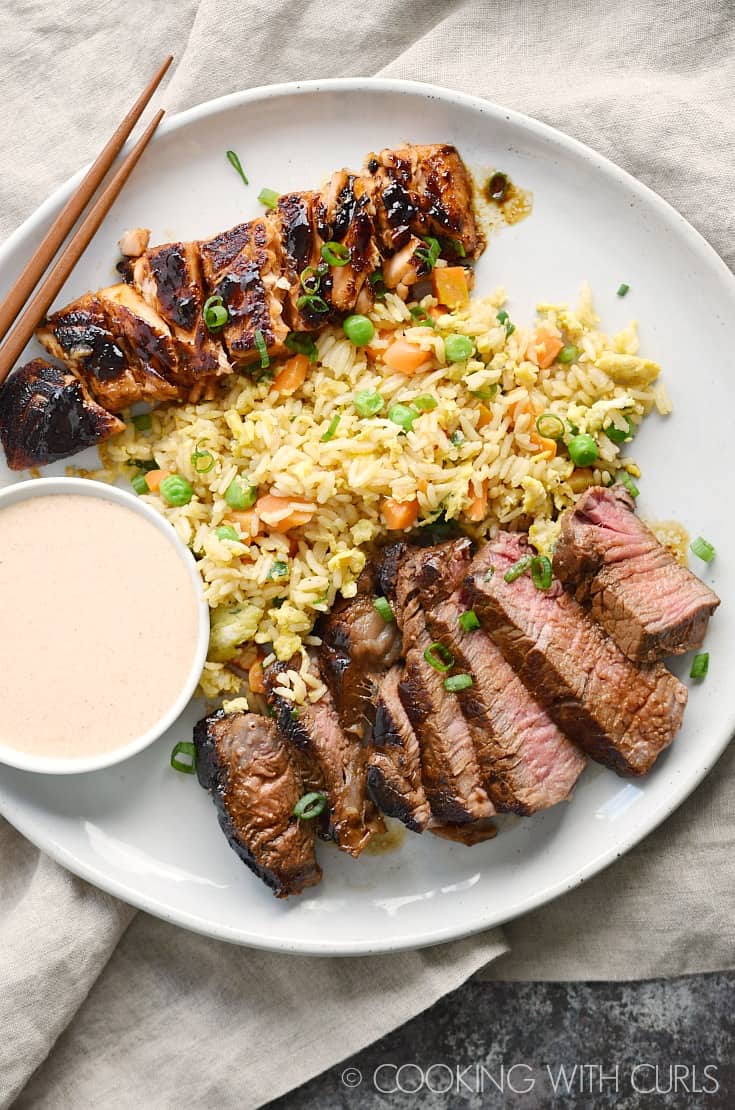 Steak and Salmon with fried rice and a small bowl of Yum Yum Sauce on a large plate.