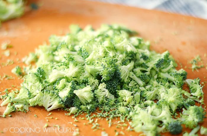 Broccoli chopped into small pieces on a cutting board.