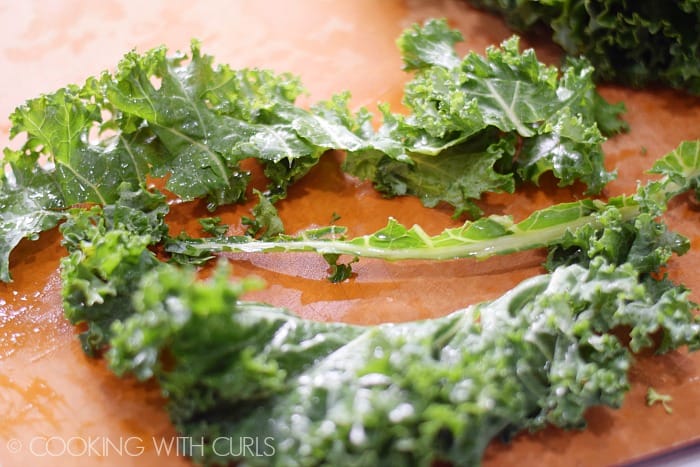 Kale with the rib cut out of the center on a cutting board.