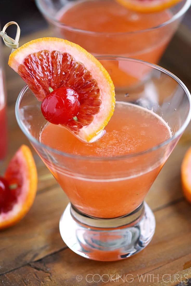 Blood Orange Martinis in short glasses garnished with an orange slice and cherry.