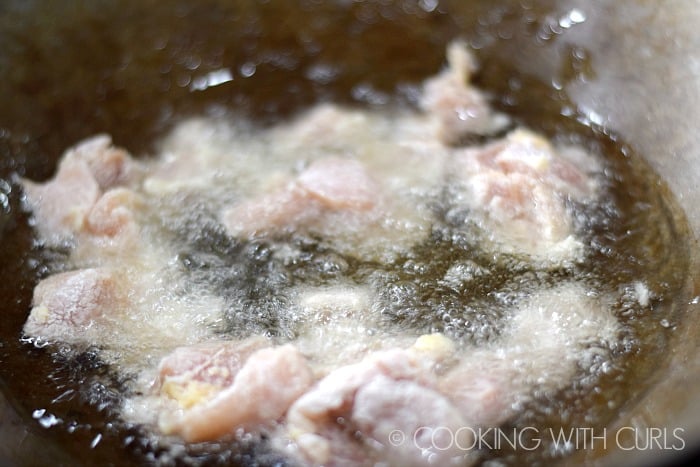 Chicken pieces frying in an oil filled wok