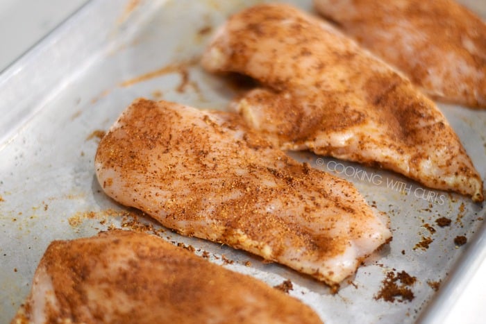 A baking sheet with Tandoori Spice Mix rubbed over the chicken breasts.