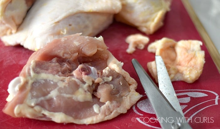 Excess skin removed from chicken thigh with kitchen shears.