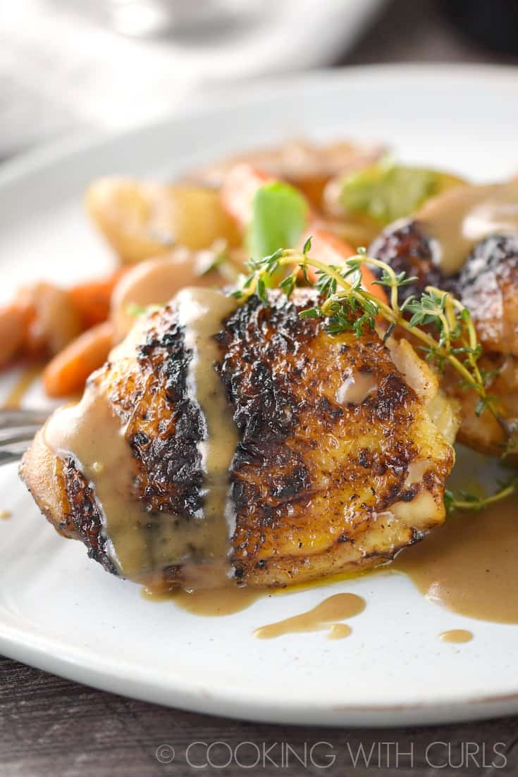 Guinness Beer-Braised Chicken Thighs drizzled with gravy on a dinner plate.