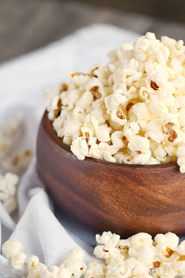 A wooden bowl overflowing with popcorn.
