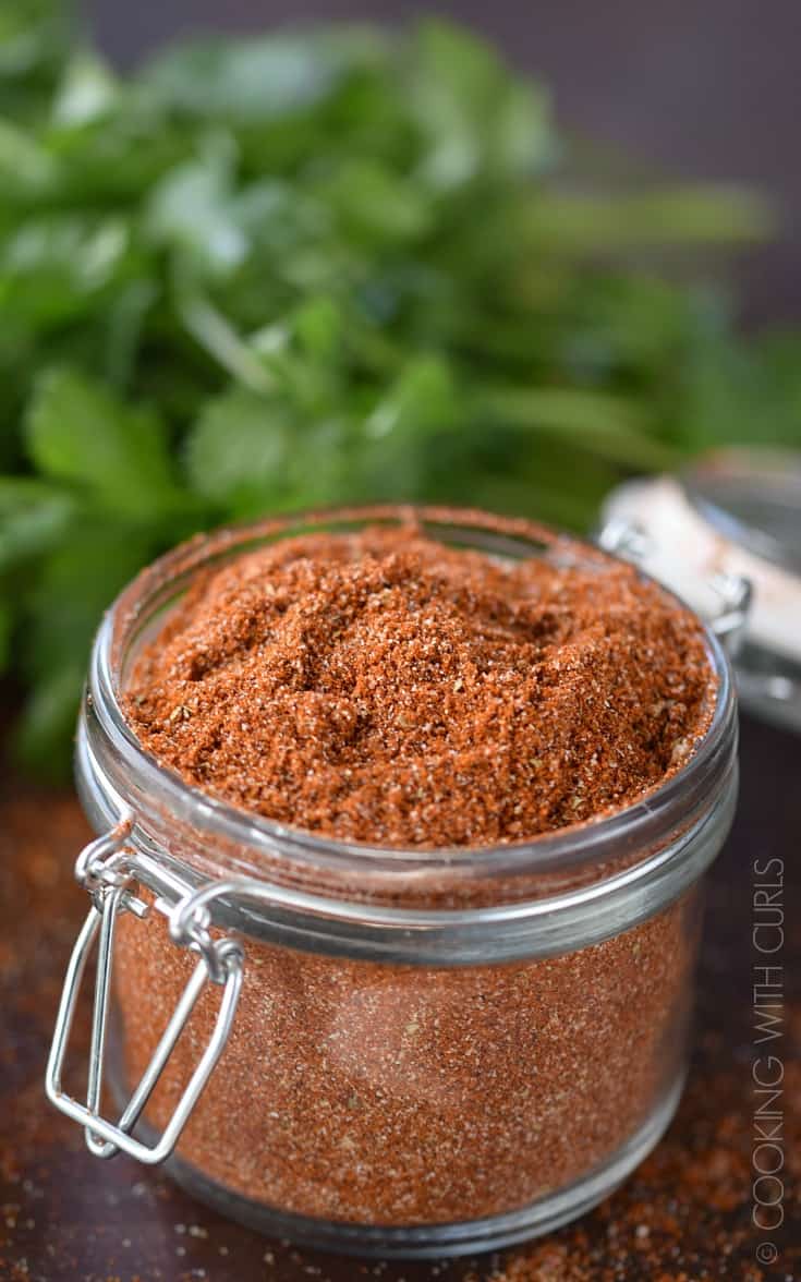 Chili, onion, and garlic powder combined with paprika, cumin, salt and pepper in a small glass jar.