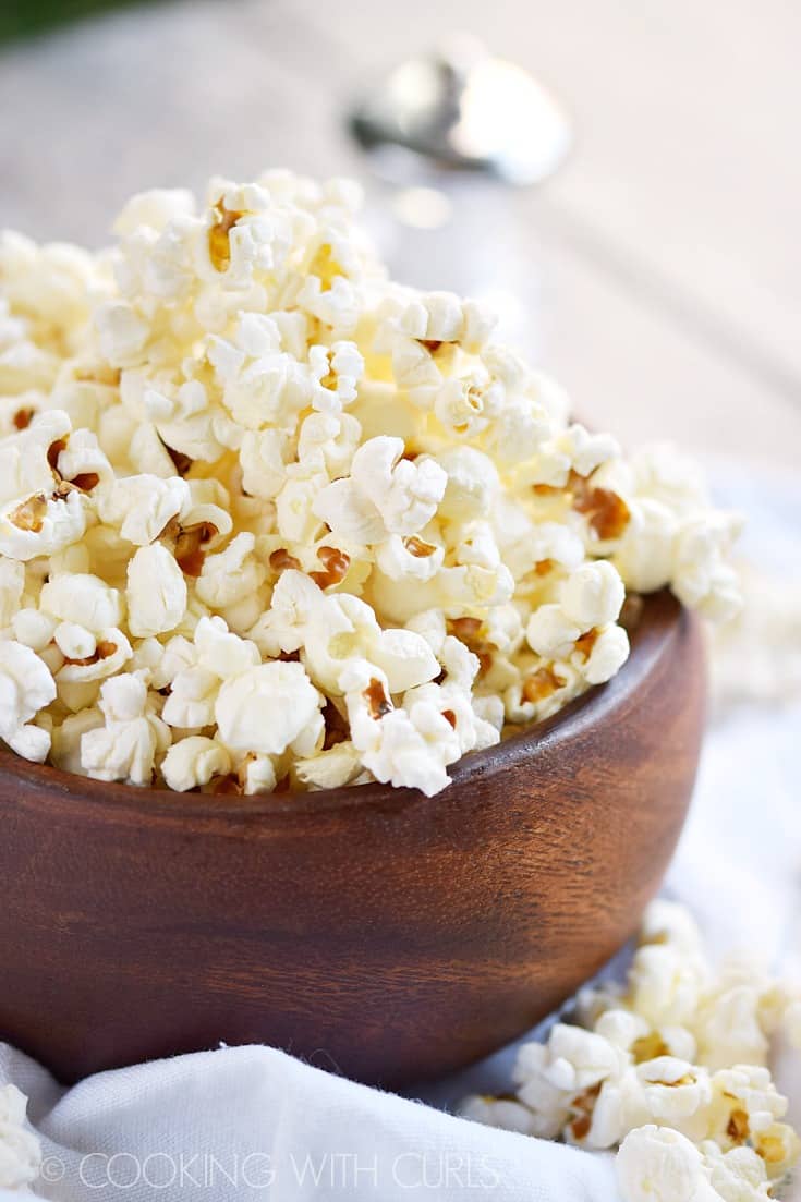 Fluffy popcorn overflowing a small wooden bowl.