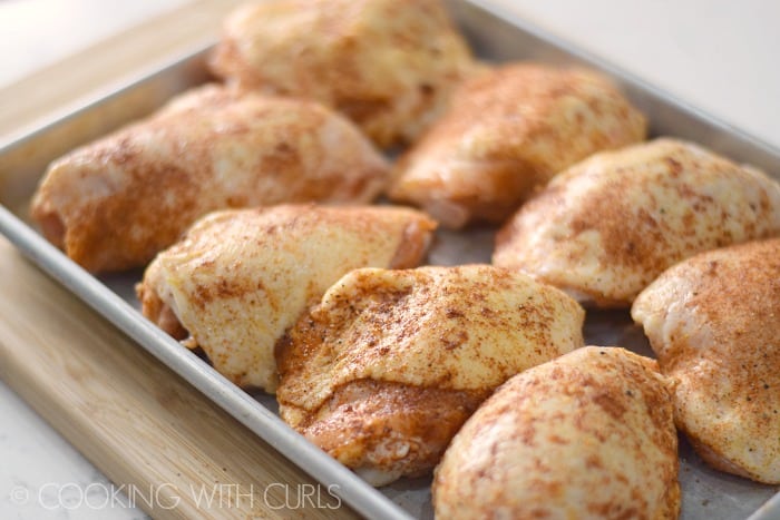 Spice rubbed chicken thighs resting on a baking sheet © COOKING WITH CURLS