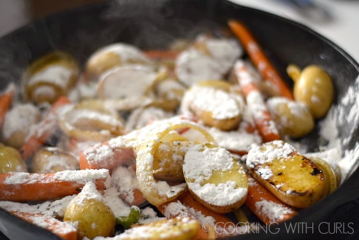 Flour sprinkled over the vegetables in the cast iron skillet.