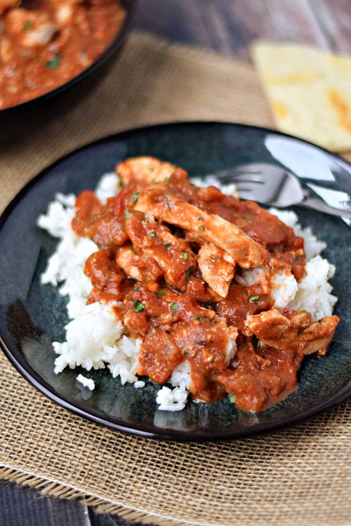 Pieces of chicken in masala sauce over rice.