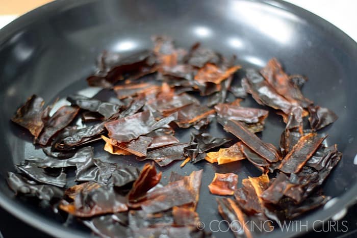Chunks of dried chilies roasting in a non-stick pan © COOKING WITH CURLS