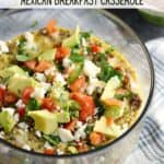 Mexican Breakfast Casserole in a clear glass bowl topped with diced tomatoes, avocado and green onions.