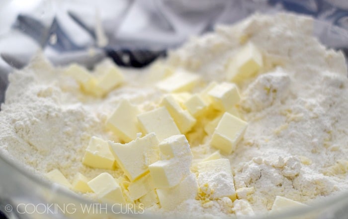 Butter cubes added to the dry ingredients in a large mixing bowl.