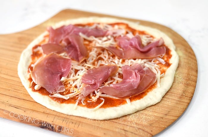 Thin slices of prosciutto on top of the pizza.
