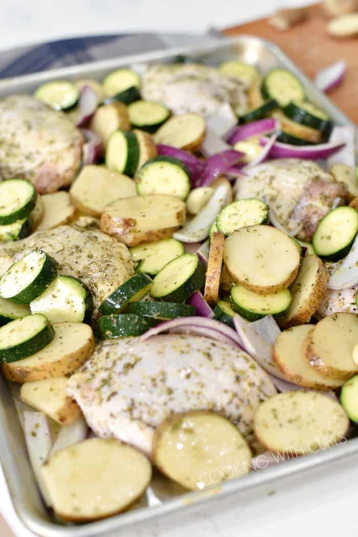 Place seasoned chicken and vegetables on a baking sheet © COOKING WITH CURLS